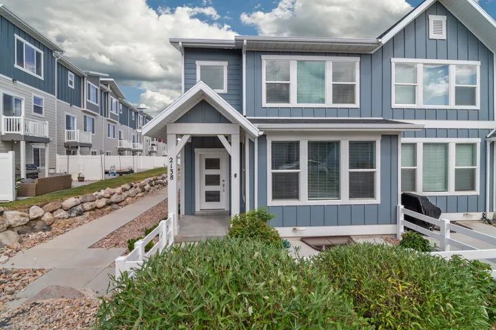 Modern townhome exterior featuring blue vertical siding with white trim