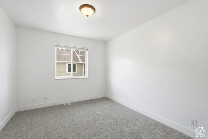 Light gray carpeting with bright white walls, white trim, and a white window frame