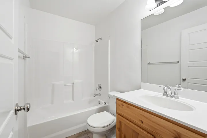 Bathroom featuring a wood-finish vanity with a white countertop, an oval undermount sink, and a chrome faucet