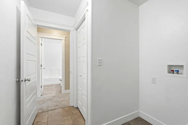 Utility area featuring a laundry hookup with water lines, a standard electrical outlet, and white baseboards
