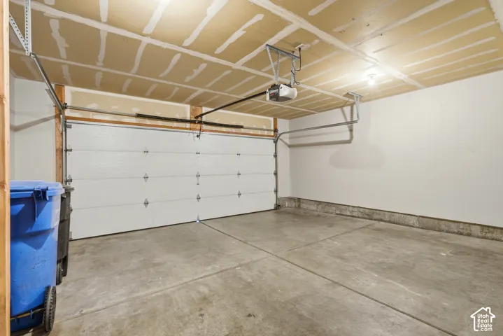 Single-bay garage with a concrete floor, white panel garage door, and an automatic garage door opener