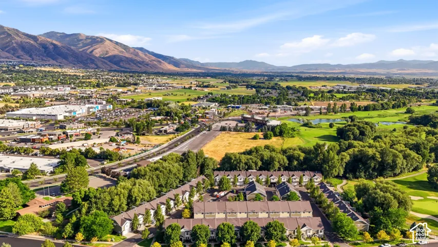 Townhome community surrounded by green spaces and mature trees, featuring pitched roofs and varied exterior finishes