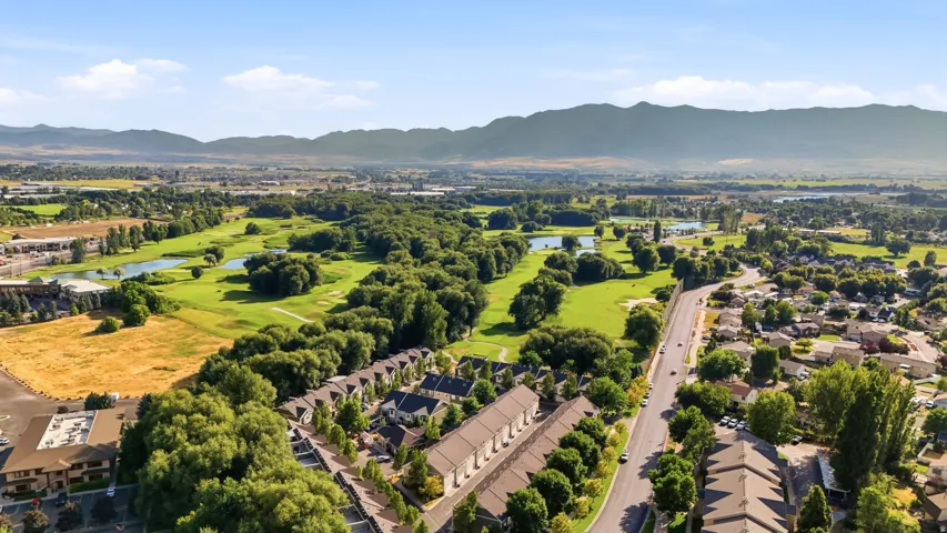 Aerial perspective showcasing residential properties bordering a manicured golf course with multiple water features