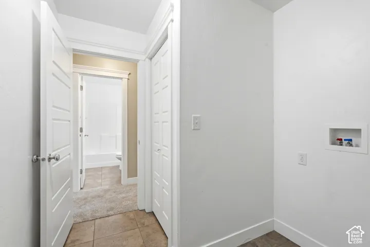 Utility area featuring a laundry hookup with water lines, a standard electrical outlet, and white baseboards