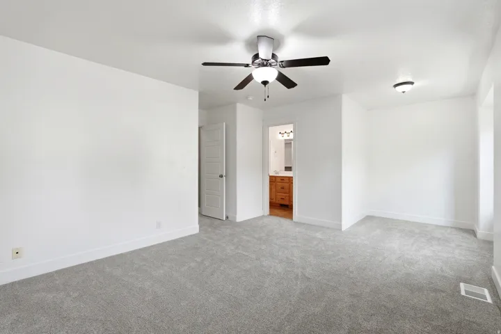 Spacious carpeted room with a ceiling fan, recessed lighting, and a five-panel interior door