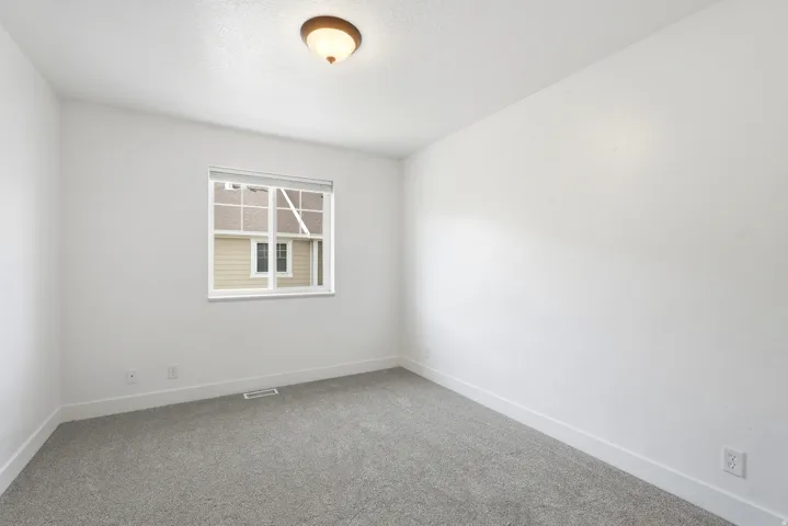 Light gray carpeting with bright white walls, white trim, and a white window frame