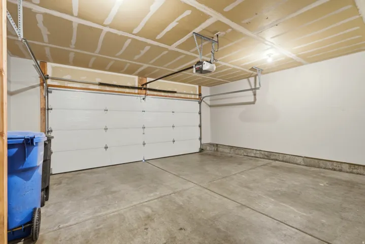 Single-bay garage with a concrete floor, white panel garage door, and an automatic garage door opener