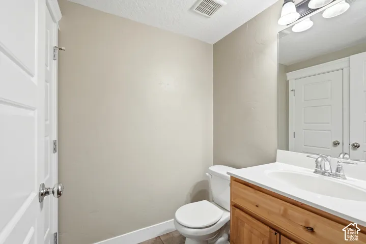 Bathroom featuring a wood-finish vanity with a white countertop and integrated sink, a chrome two-handle faucet, and a large wall-mounted mirror