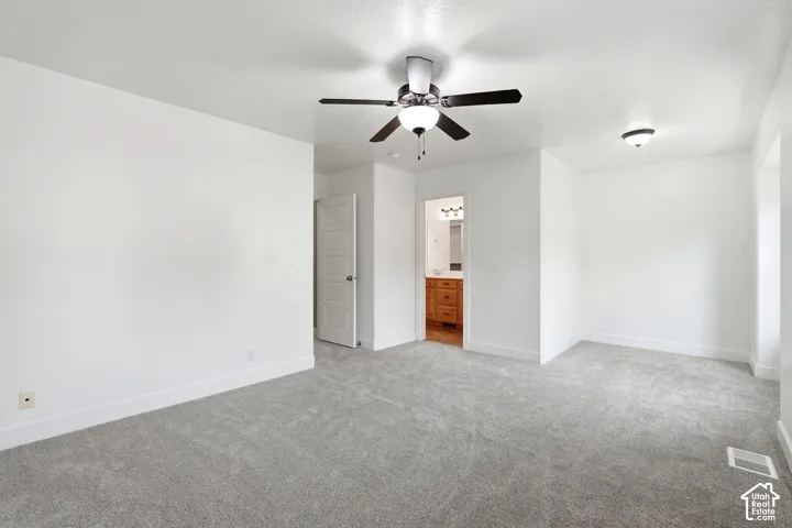 Spacious carpeted room with a ceiling fan, recessed lighting, and a five-panel interior door