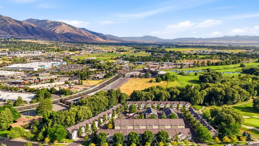 Townhome community surrounded by green spaces and mature trees, featuring pitched roofs and varied exterior finishes
