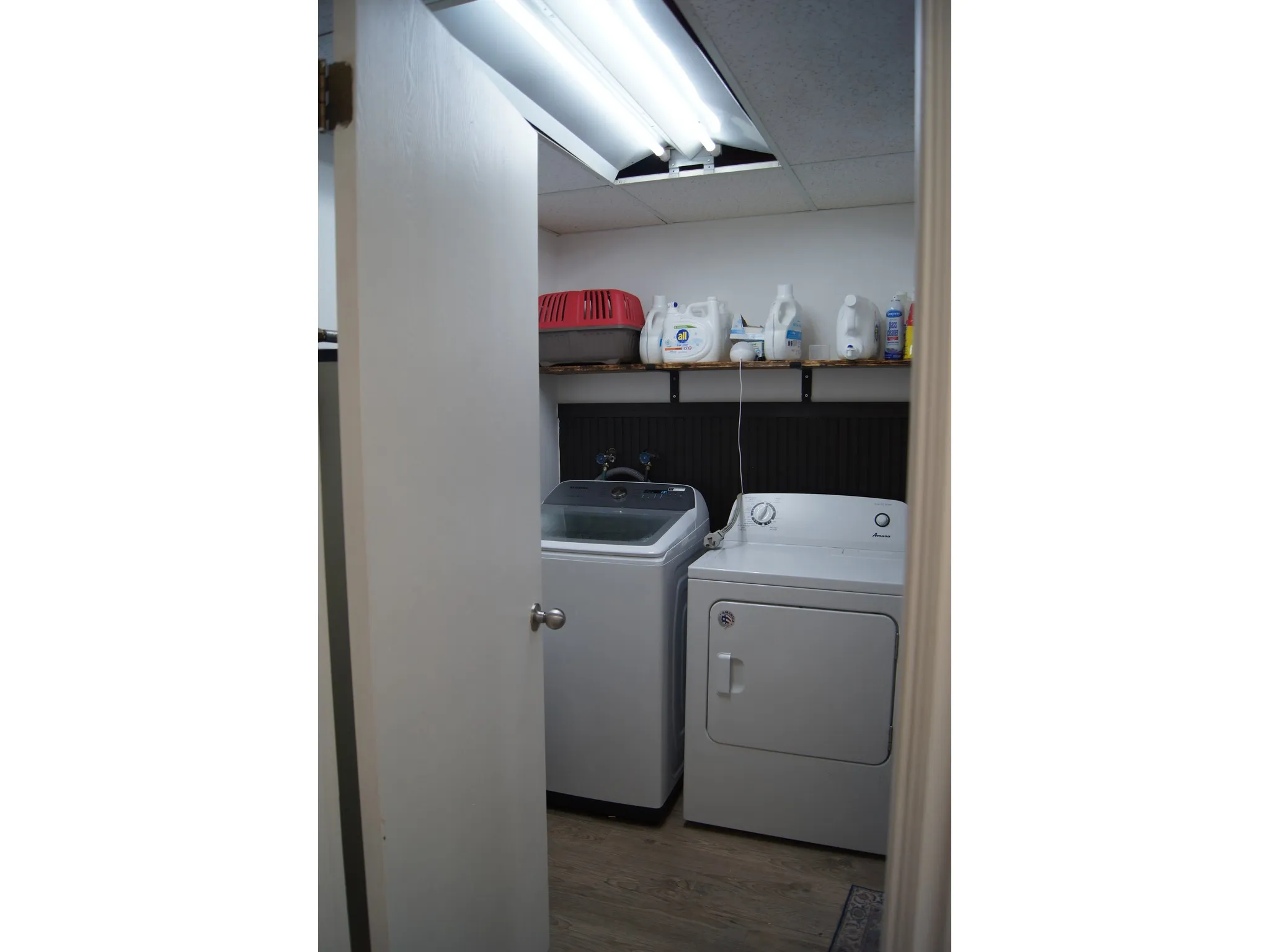 Dedicated laundry area featuring a washer and dryer, wood-finish flooring, and wall-mounted shelving