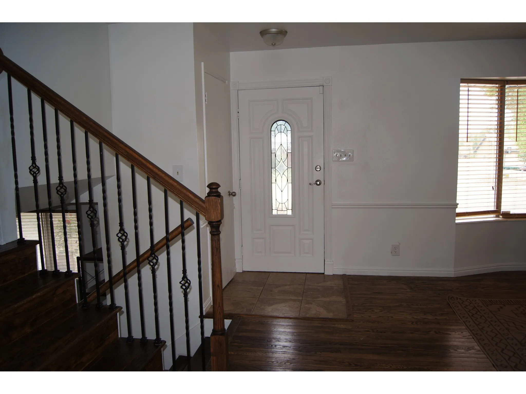 Entryway featuring a decorative front door with leaded glass, wainscoting, and wood-finish flooring