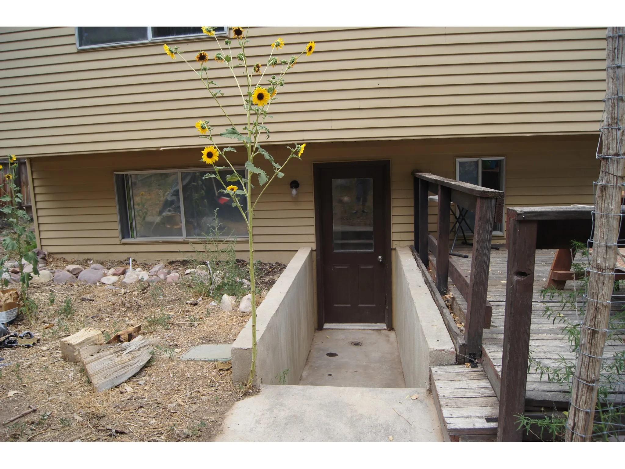 Exterior entry featuring a dark-paneled door, concrete steps, and a wooden deck with railing
