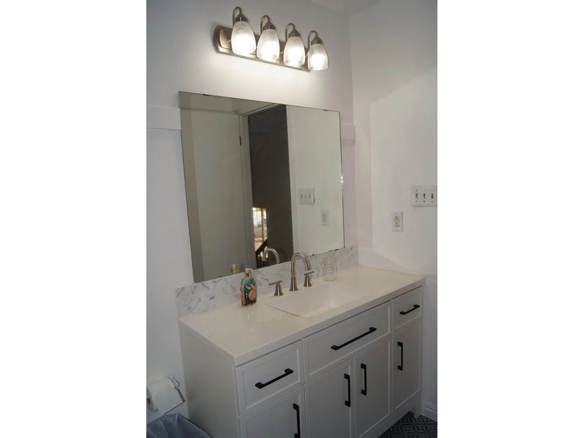 White shaker-style vanity with an integrated sink, brushed nickel faucet, and quartz countertop