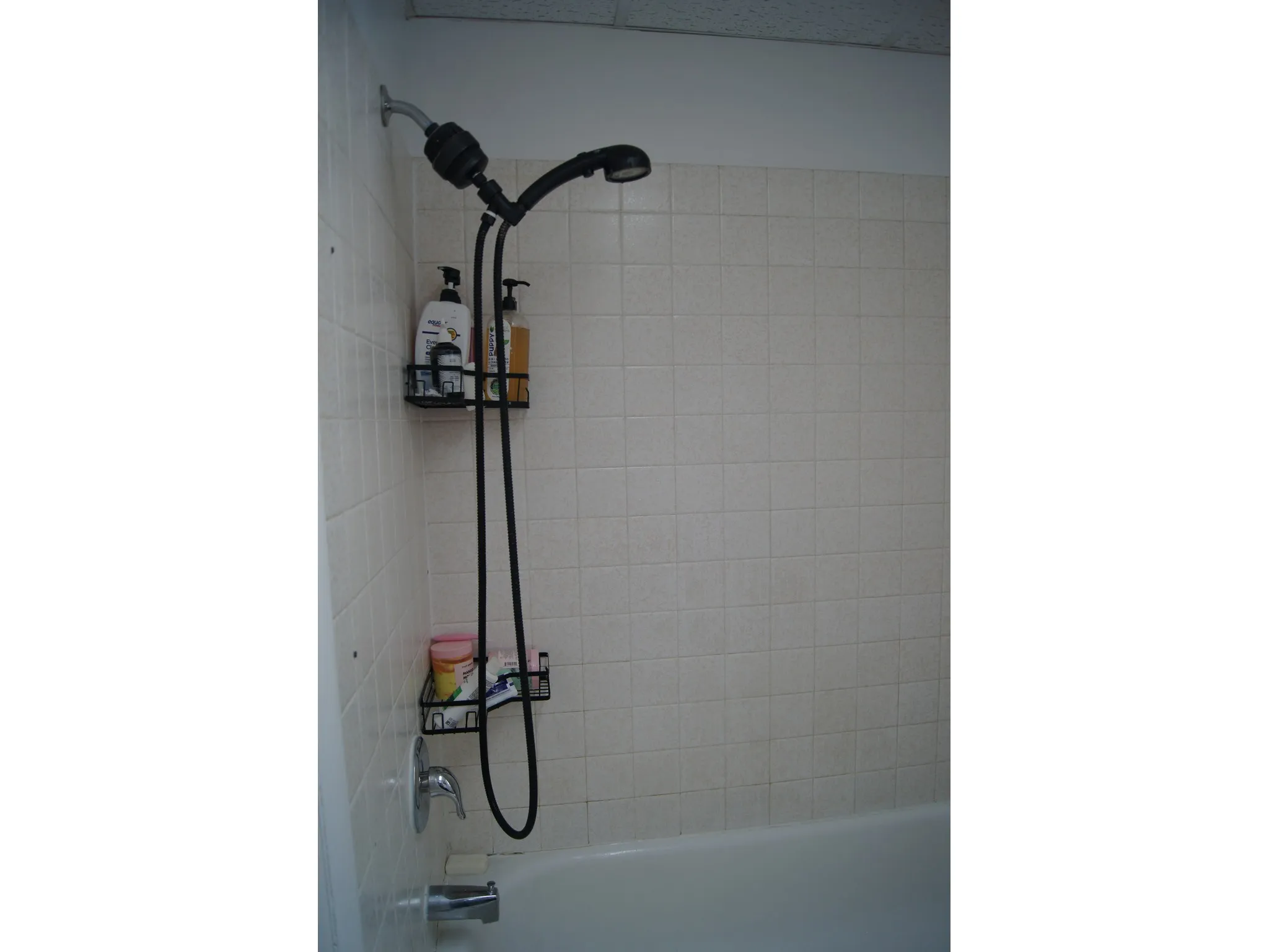 Bathtub and shower combination featuring a tiled surround and chrome fixtures