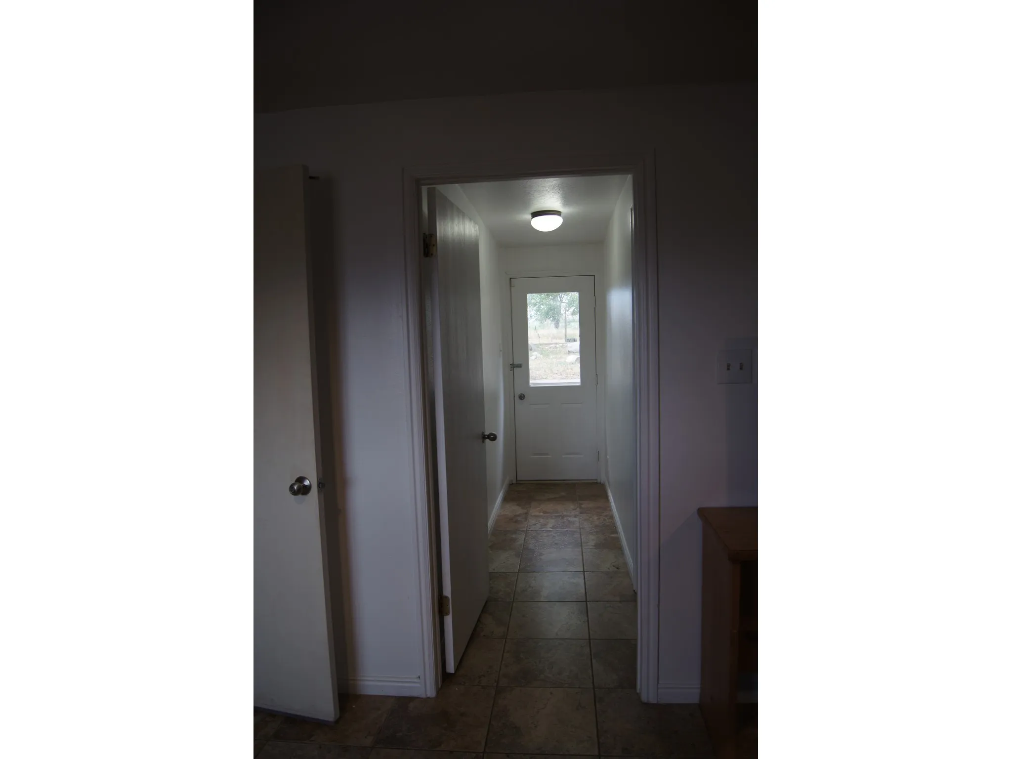 Hallway featuring tile flooring, white interior doors, and a flush-mount ceiling light