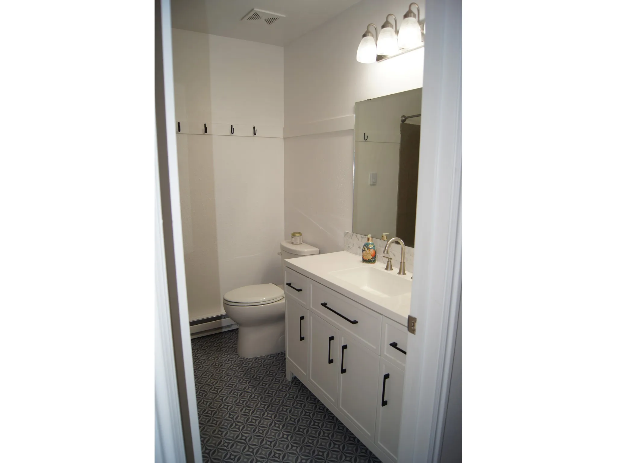 Bathroom featuring a white vanity with black hardware, an integrated sink, and a brushed nickel faucet