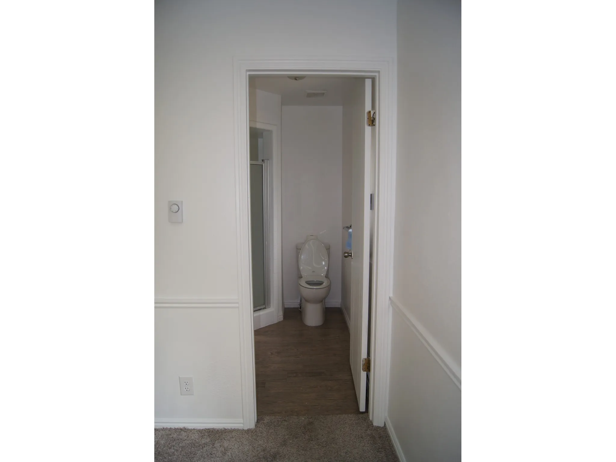 Master Bedroom Bathroom featuring a white toilet, glass-enclosed shower, and wood-finish flooring