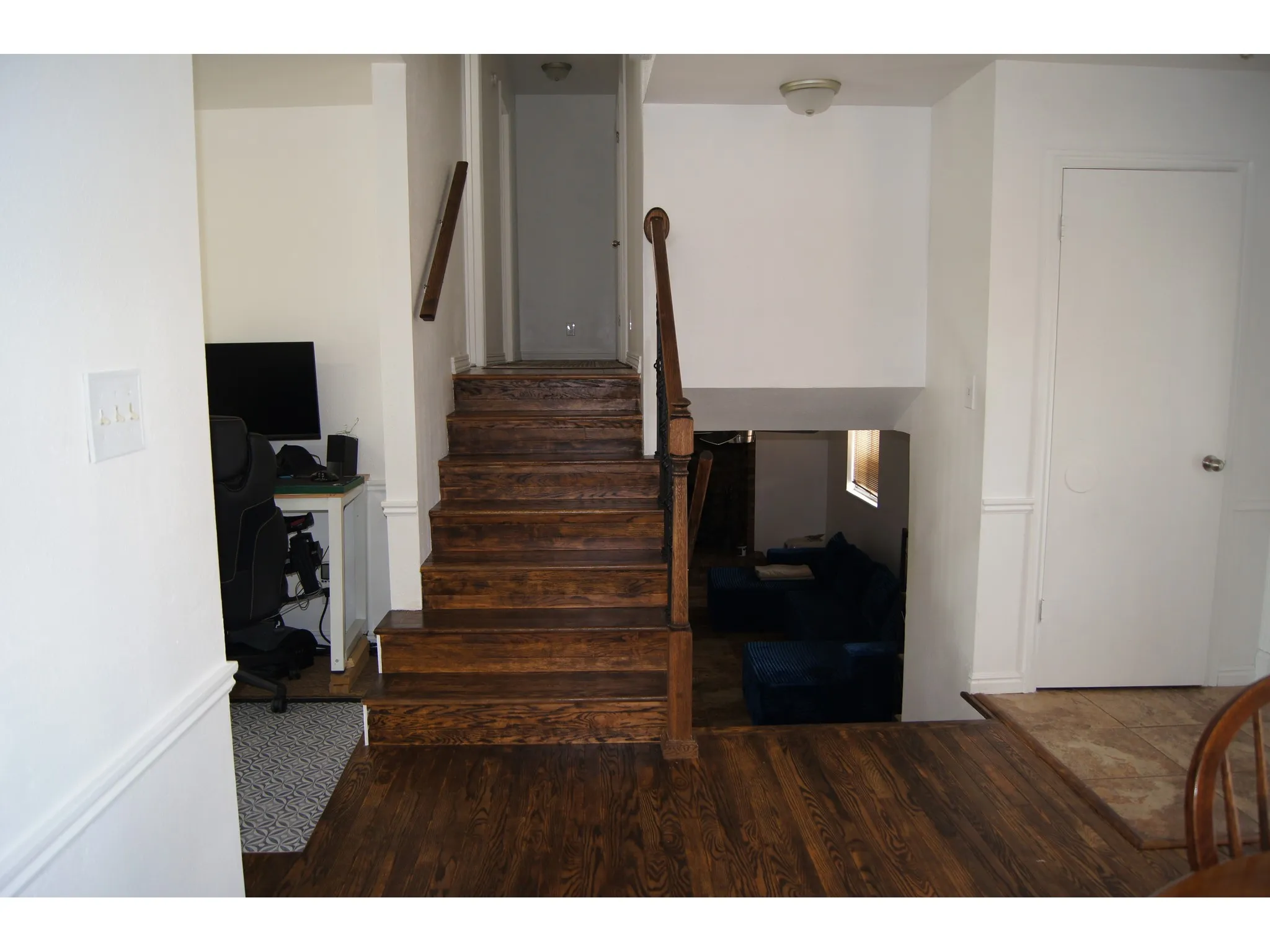 Dark wood-finish flooring extending to a matching staircase with a wooden banister