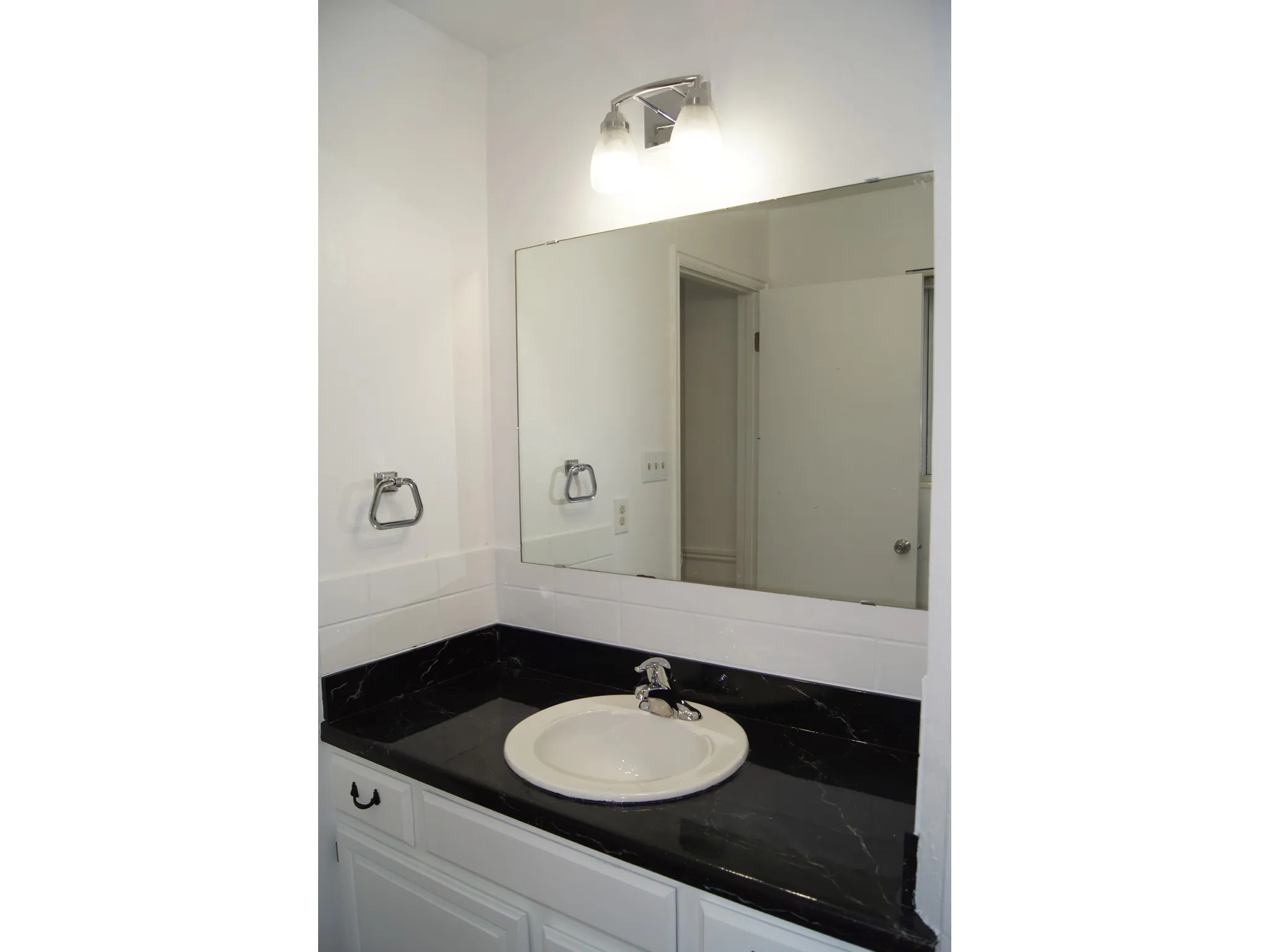 Master Bedroom Bathroom vanity with a black countertop, integrated white sink, and chrome faucet