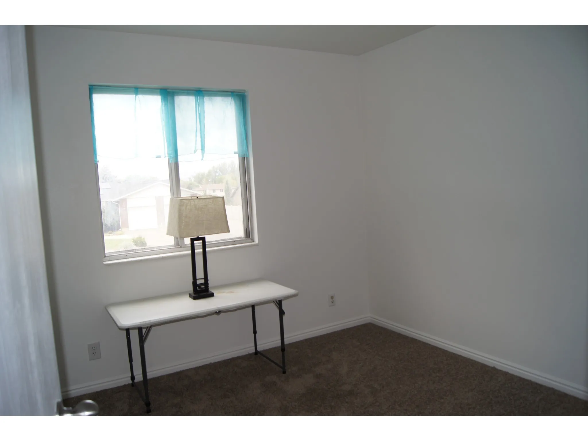 Bedroom 1 Bright interior room with a window, white walls, and carpet flooring