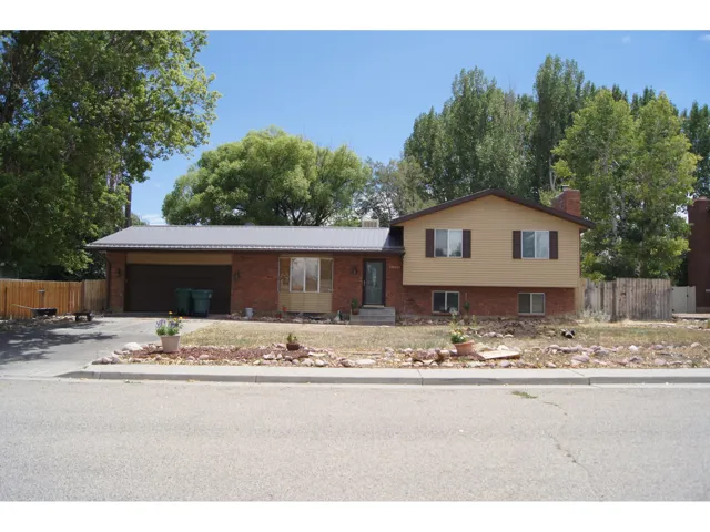 Split-level residence featuring brick and siding exterior, a metal roof, and an attached two-car garage