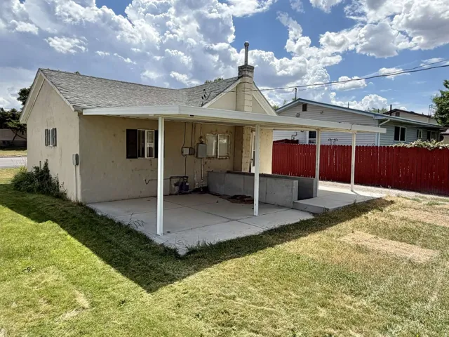 Rear exterior featuring a covered patio with a concrete slab, stucco siding, and a gabled roof