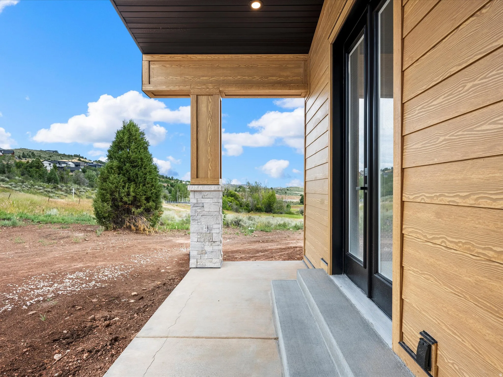 Entryway featuring light wood-finish siding and a black-framed glass door