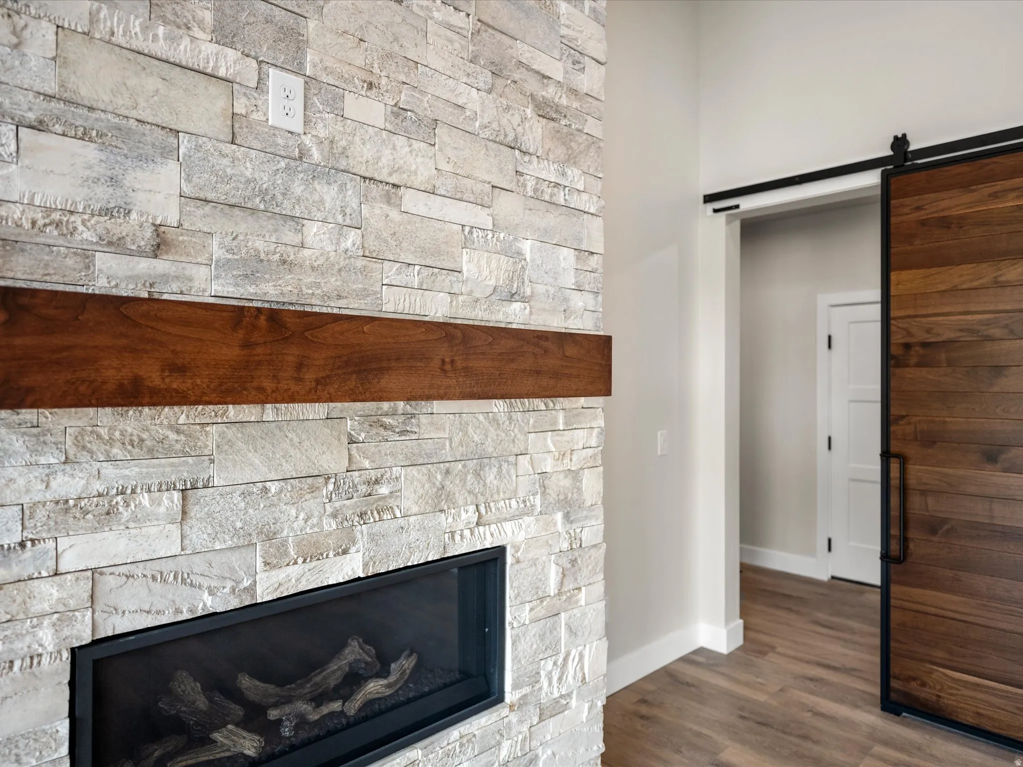 Stacked stone fireplace featuring a wood mantel and linear firebox