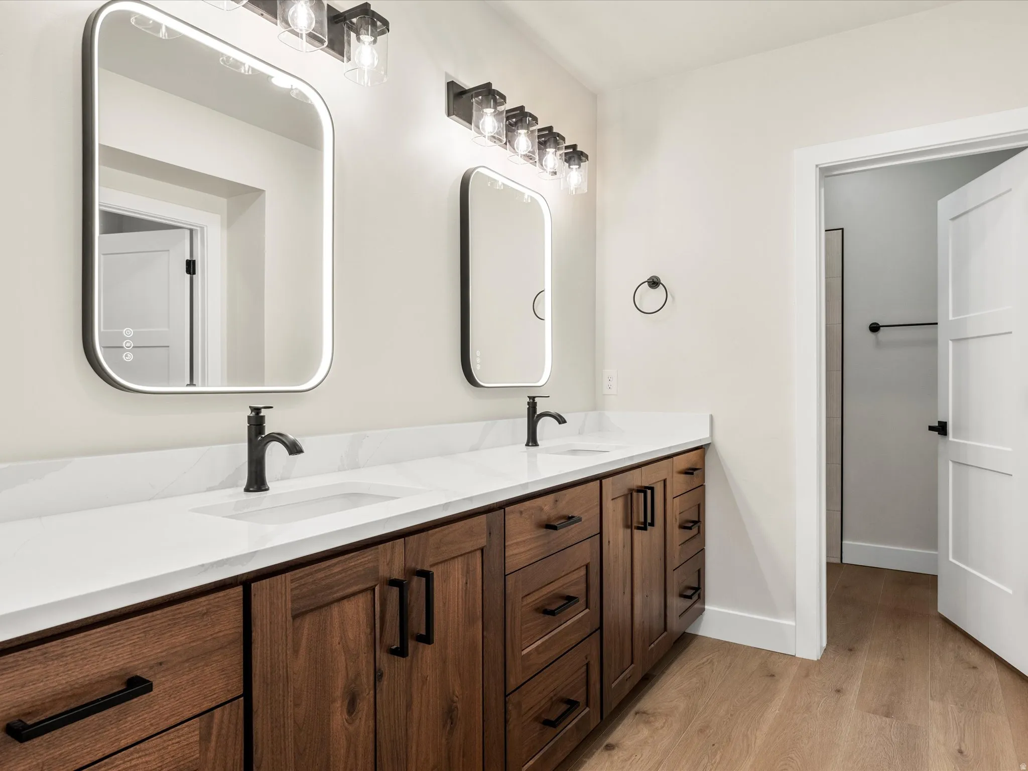 Dual vanity with wood-finish cabinetry, white countertop, and integrated sinks