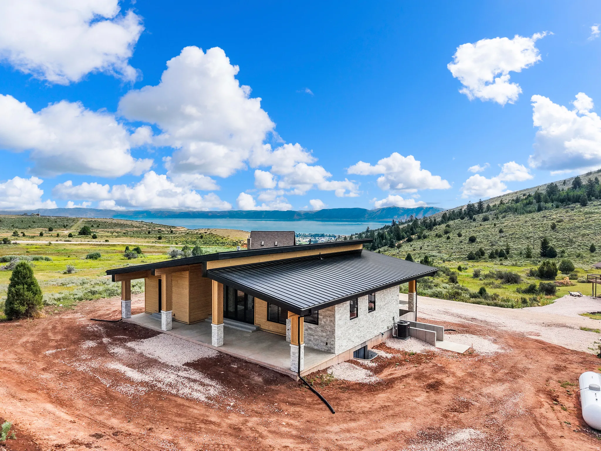 Modern residence featuring a black metal roof and stone veneer siding