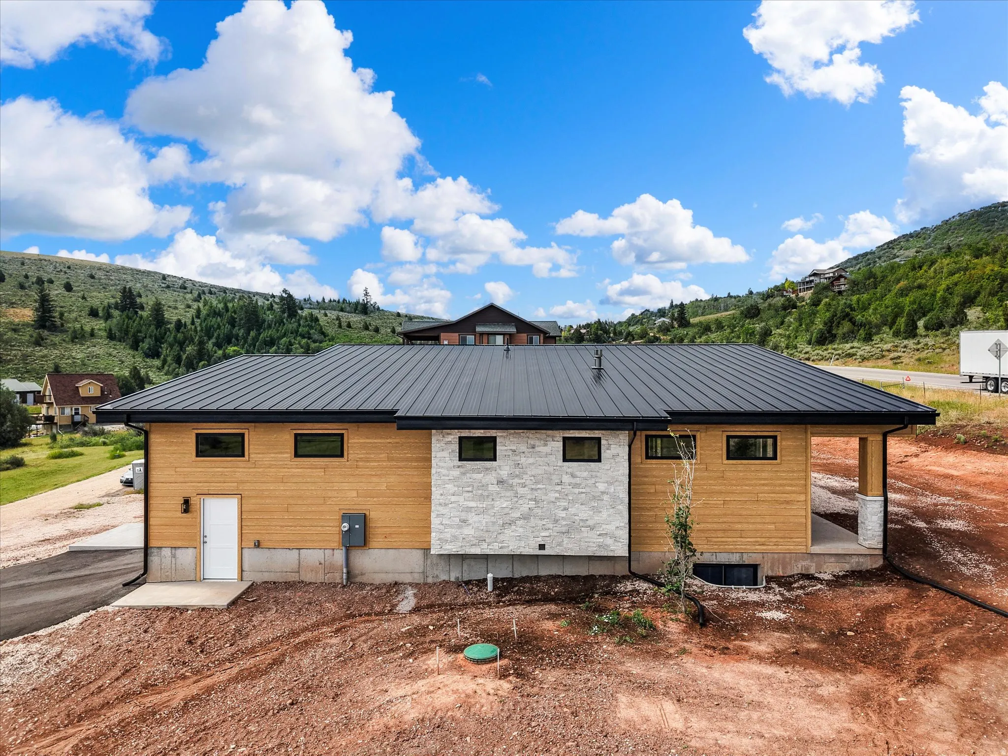 Contemporary exterior featuring horizontal wood siding, a dark metal roof, and a stone accent wall