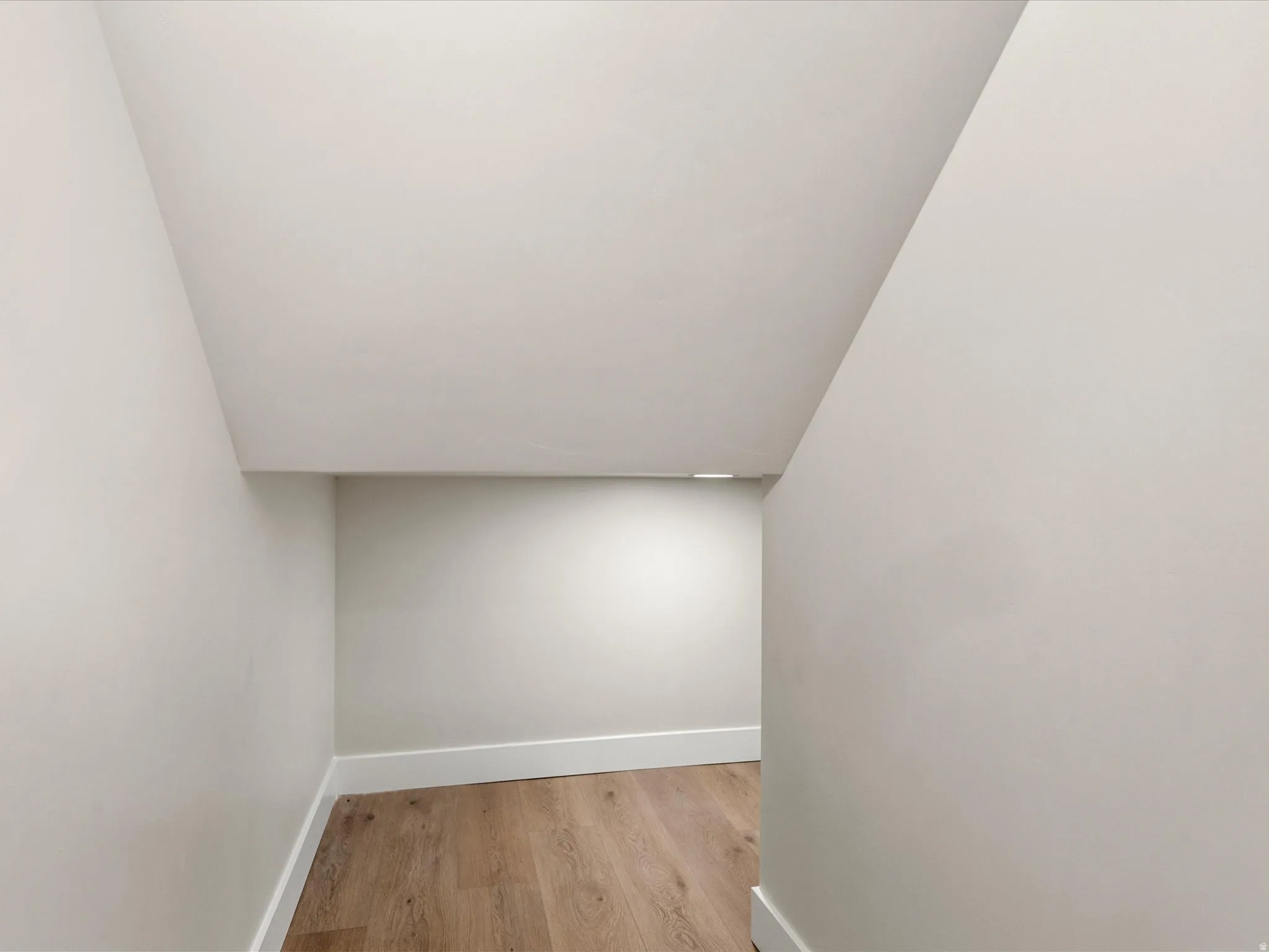 Storage area featuring light wood-finish flooring, white baseboards, and neutral wall paint