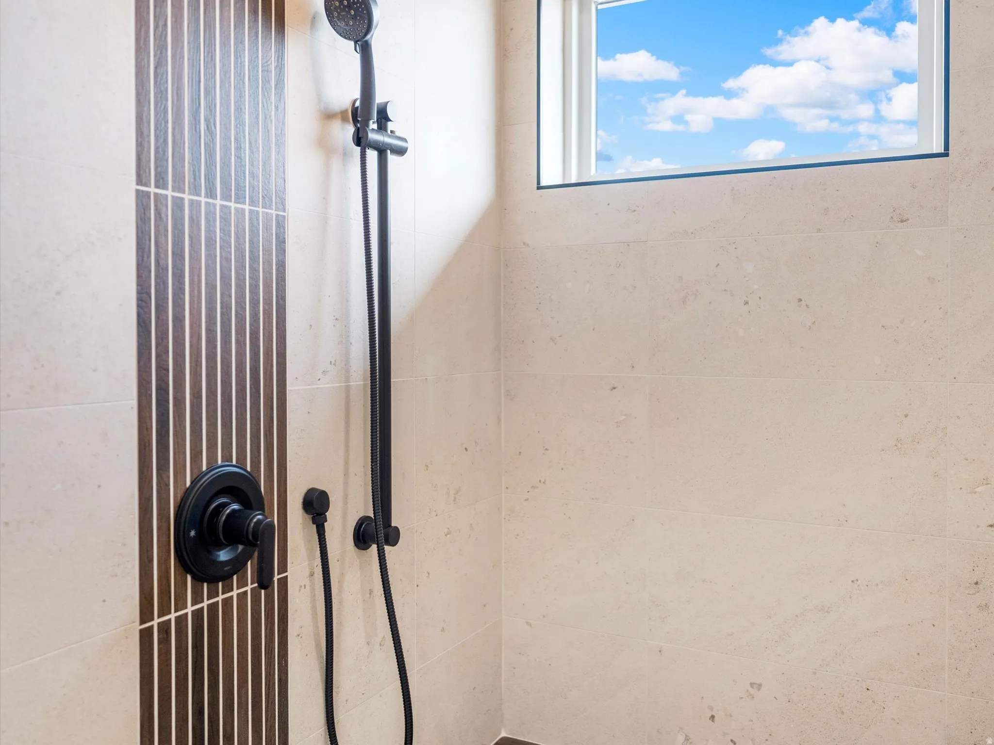 Shower with matte black fixtures, an adjustable showerhead, and a rectangular window
