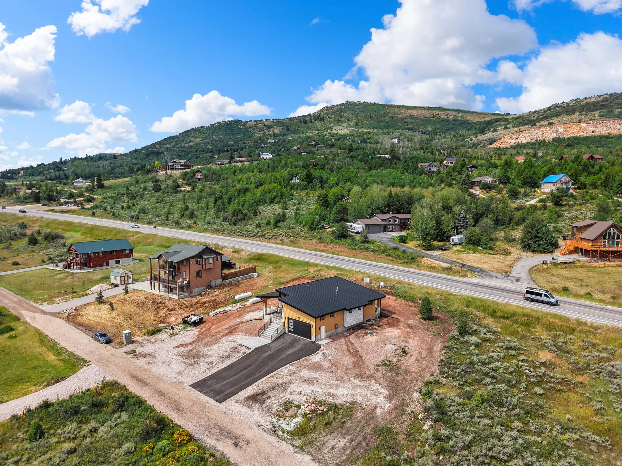 Modern single-story residence under construction featuring a black roof and light-colored siding