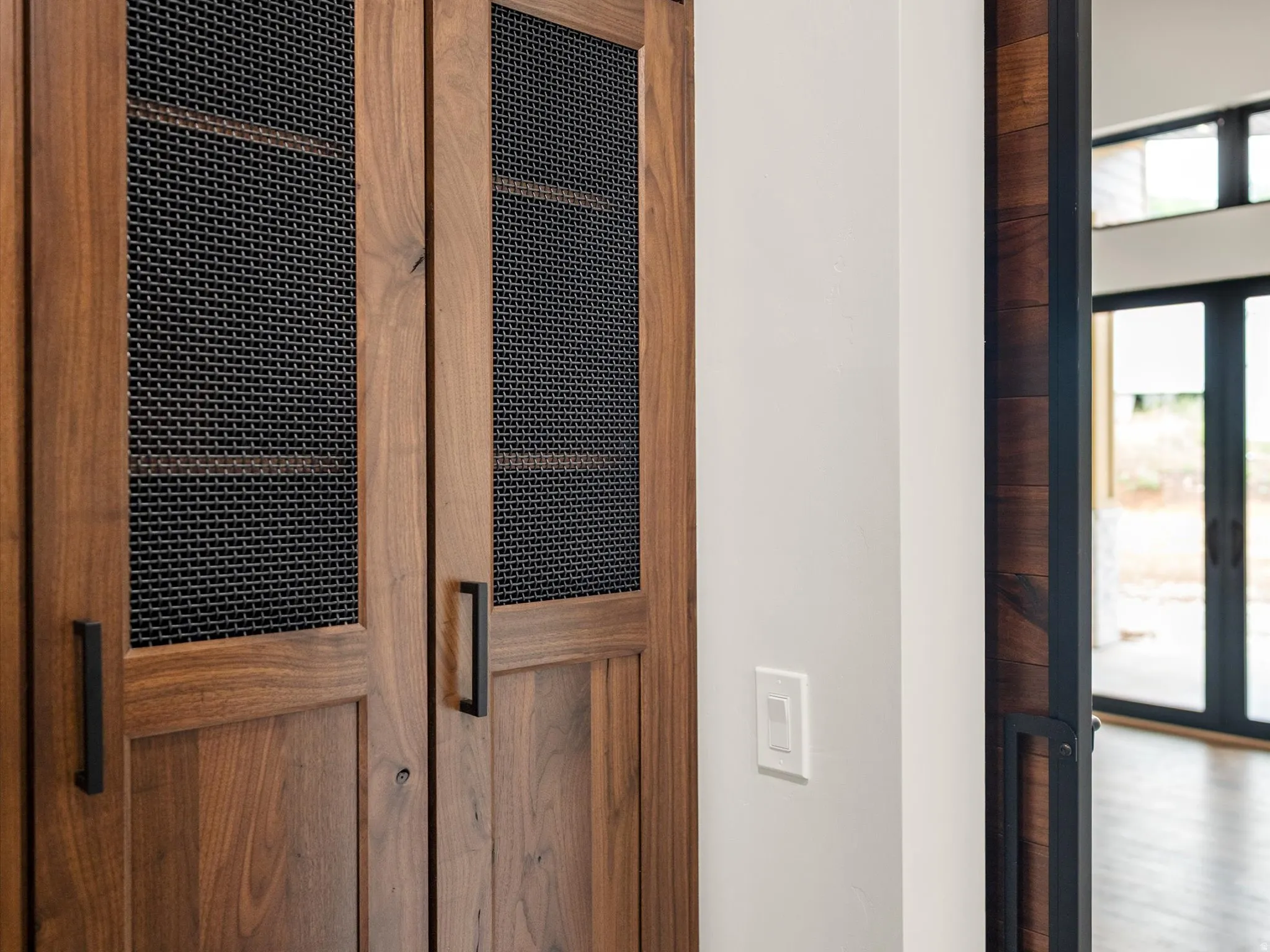 Wood-paneled doors with mesh inserts, complemented by matte black hardware