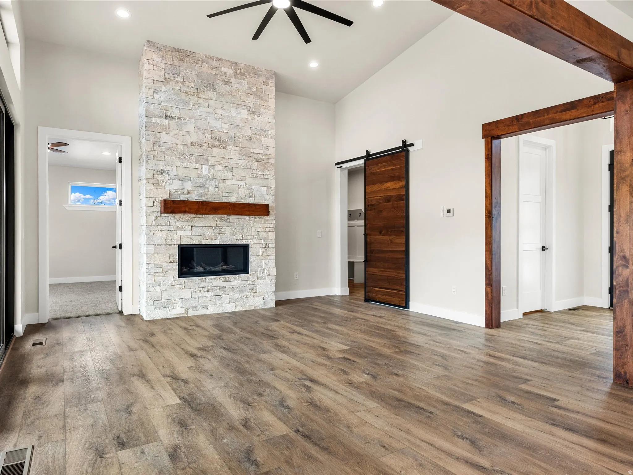 Spacious living area featuring a floor-to-ceiling stone fireplace with an integrated linear firebox and a wood mantel
