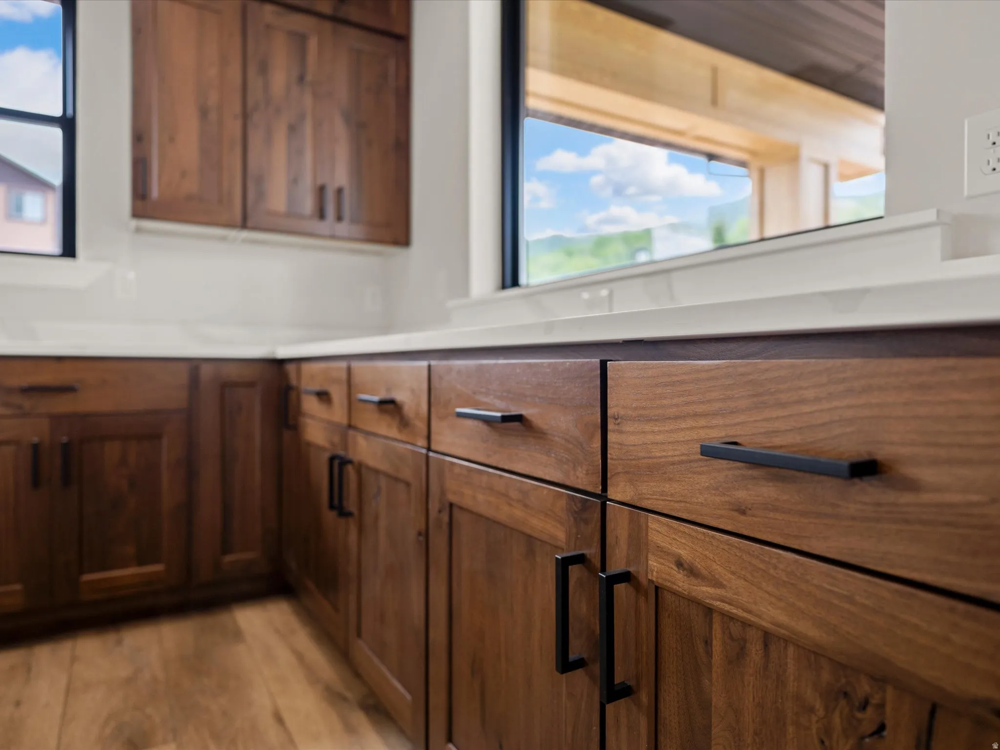 Kitchen featuring wood-finish cabinetry with matte black hardware, white countertops, and a full-height backsplash