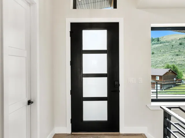 Contemporary black entry door with frosted glass panels, transom window, and modern black hardware