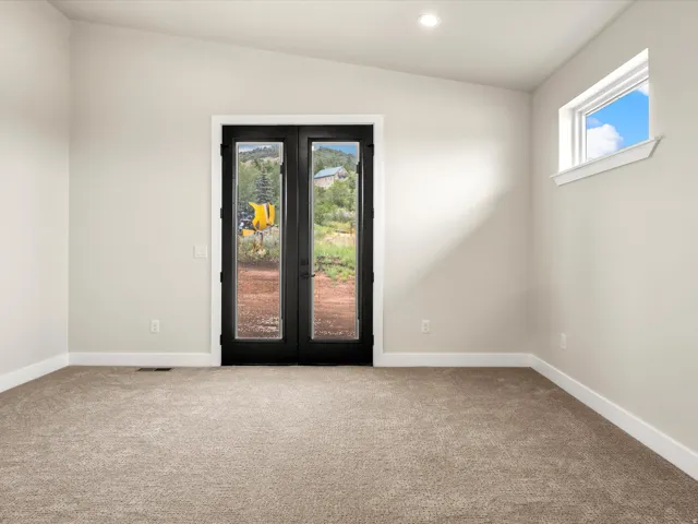 Room featuring a vaulted ceiling with recessed lighting, light beige carpeting, white baseboards, and neutral wall paint
