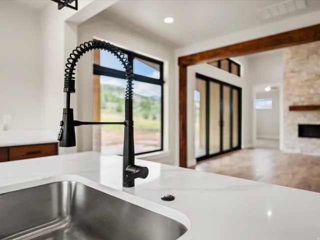 Kitchen sink with a matte black coil spring faucet, a stainless steel basin, and a white countertop