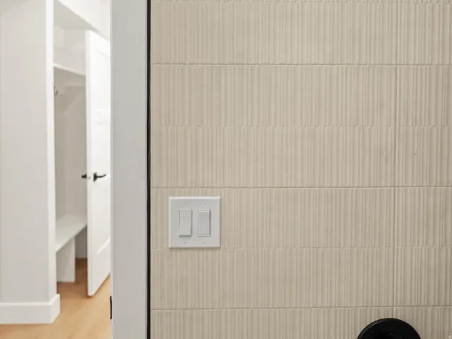 Textured wall paneling featuring white light switches and a black circular fixture