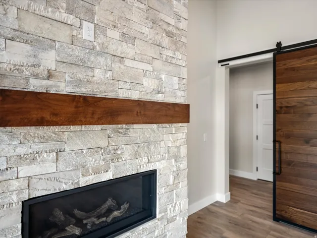 Stacked stone fireplace featuring a wood mantel and linear firebox