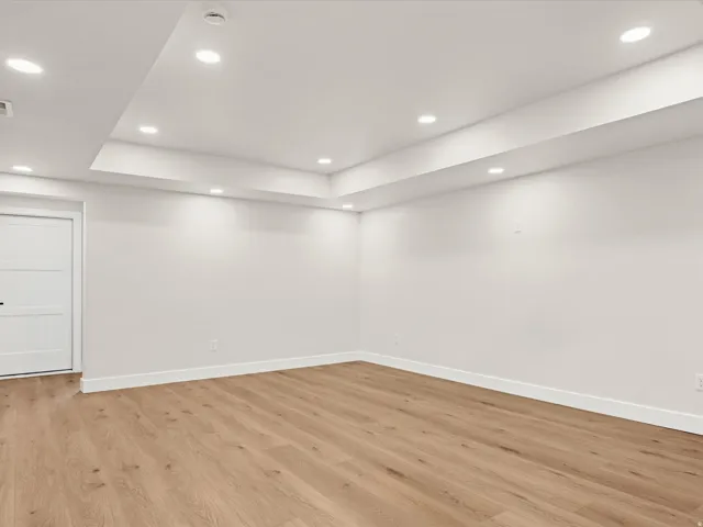 Bright interior space featuring light wood-finish flooring, white walls, and a multi-level ceiling with recessed lighting