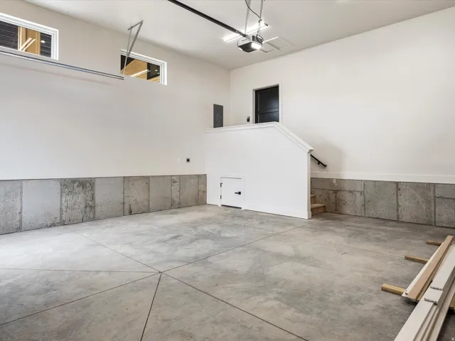 Spacious garage featuring a concrete floor with geometric scoring, concrete wainscoting, and high transom windows