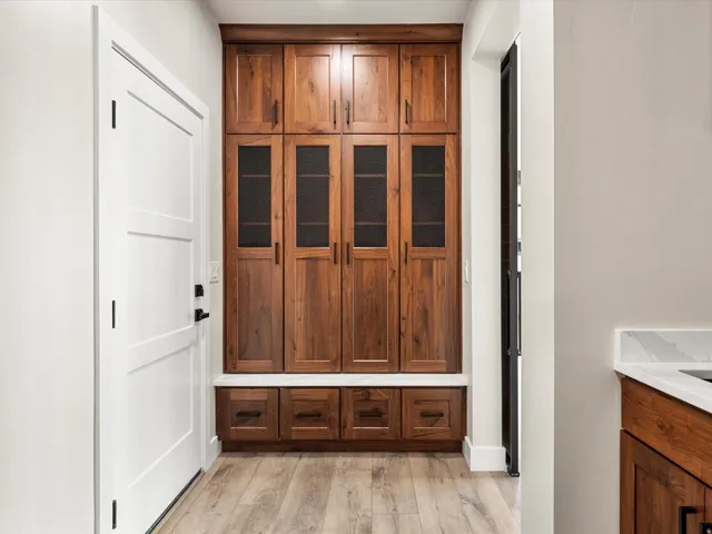 Custom wood cabinetry featuring both solid panel and glass-front doors, complemented by a white countertop and wood-finish flooring