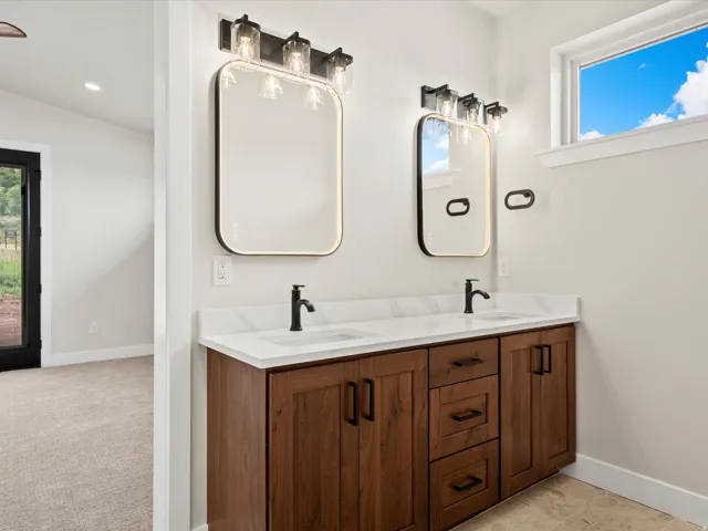 Dual vanity featuring wood-finish cabinetry, white countertops, and matte black fixtures
