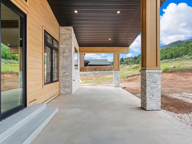 Covered patio featuring a concrete surface and stone-clad support pillars