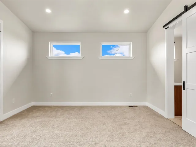 Neutral-toned room featuring two transom windows, recessed ceiling lighting, and beige carpet flooring