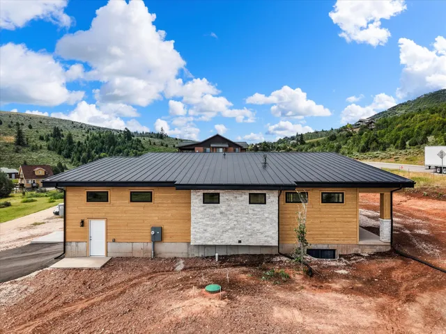 Contemporary exterior featuring horizontal wood siding, a dark metal roof, and a stone accent wall